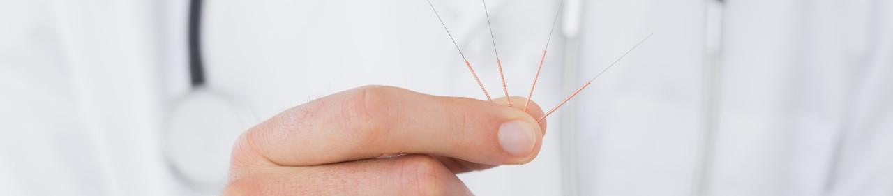 Extreme close-up mid section of a male doctor holding acupuncture needles